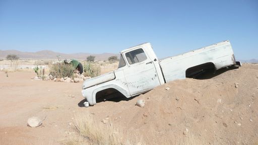 A white abandoned car in a sandy desert