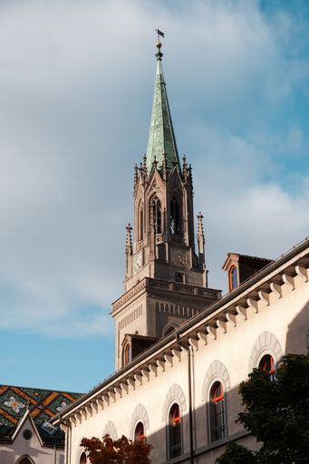 A vertical shot of a church tower behind old historic buildings  in Saint Gallen