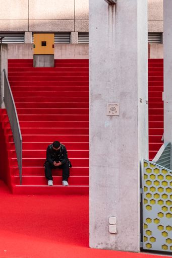 A vertical shot of a young male using a smartphone while sitting on red stairs