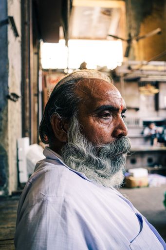 A vertical shot of an elderly Indian male with a beard