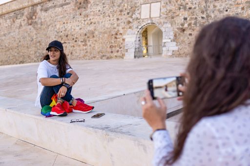 Couple of lesbian girls taking pictures of each other sitting in a park, copy space