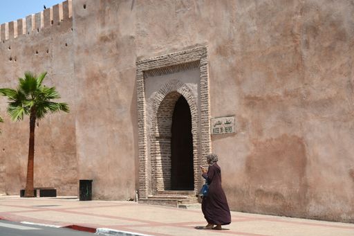 An Arabic woman walking near an old arch on a big wall in Meknes, Morocco