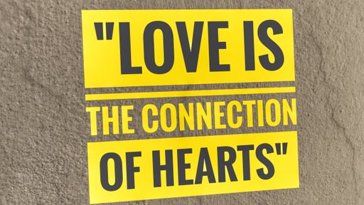 A yellow quote about love in English on a rough wall