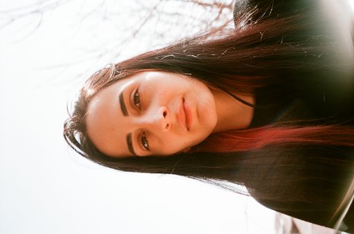 A portrait of a beautiful young Caucasian female with pink hair highlights under the sunlight shot on film