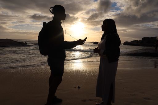A silhouette of a couple talking to each other while standing at the beach during sunset