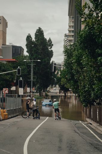 A vertical shot of cyclists assessing road conditions after heavy rainfall in Brisbane City