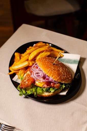 A vertical shot of a juicy hamburger with fries
