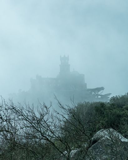 A vertical shot of a old historical castle covered with dense fog