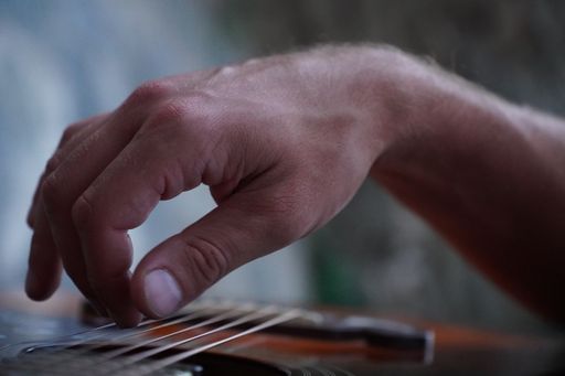 A closeup of a male hand playing a guitar