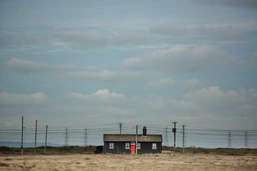 A small house on the roads under a cloudy sky