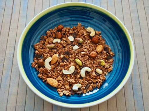 muesli with nuts in a colorful bowl plate on a washed up wooden table