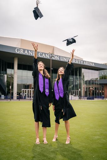 A vertical shot of two females throwing their hats during their graduation in Phoenix, Arizona