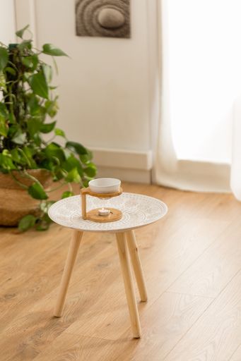 A vertical top view of essential oils for massage in a bowl on a wooden stand on a small table
