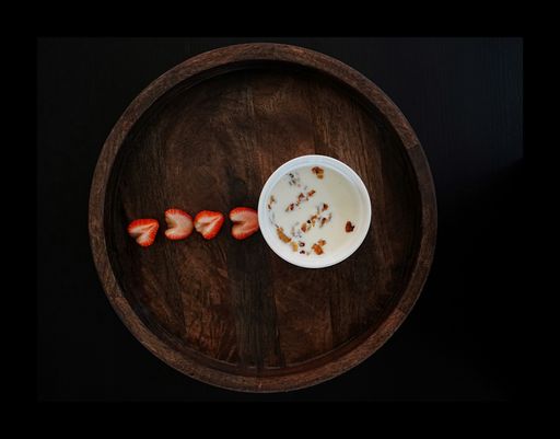 Top view of toast pieces in milk with strawberry slices on a wooden tray