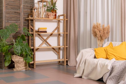 Cozy and comfortable living area: wall decorated with fabrics, sofa with yellow cushions and wooden shelf with decorative street lamps with candle.