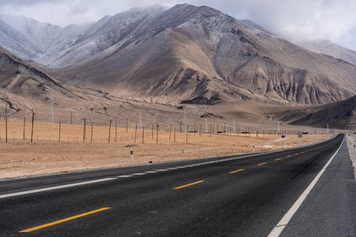 a shot of highway going to mountain covered with clouds