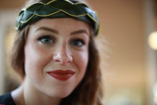 A closeup shot of a caucasian female wearing a fashionable headband smiling at the camera