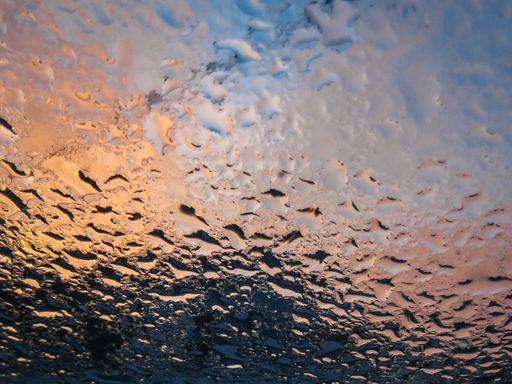 The water droplets after rain on window pane at sunrise