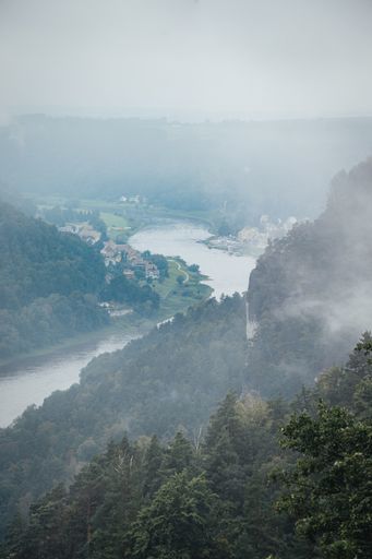 Photo looking down on the mountains at the Saxon Switzerland national park on a misty day with incredible rock formations shooting up from the ground
