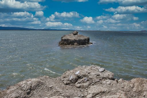A beautiful sea view with a huge rock formation in the water under the blue sky with fluffy clouds at daytime