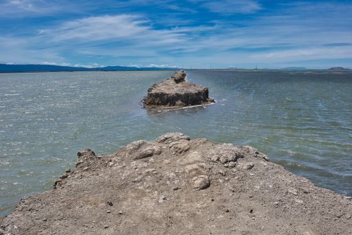 A beautiful sea view with a huge rock formation in the water under the blue sky at daytime