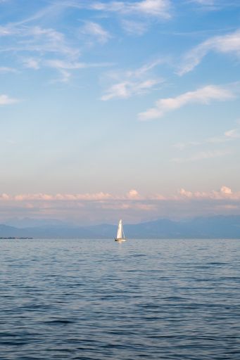 A vertical shot of a sailing ship in Lake Constance under the cloudy skies
