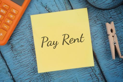 A closeup shot of a yellow notebook page with the writing pay rent