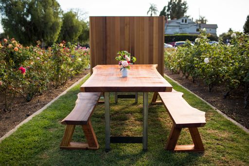 A closeup shot of a table and benches in a garden with flowers and plants on both sides