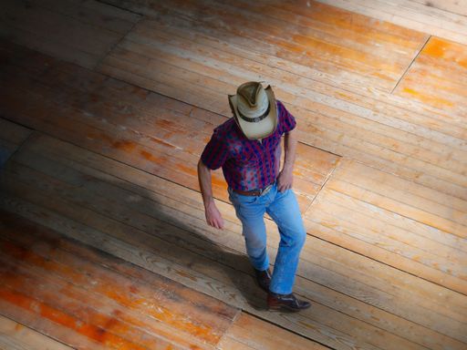 A high-angle shot of the traditional western folk music dancer wearing a cowboy hat.