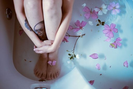 record of a girl sitting in a bathtub with lilac flowers around her