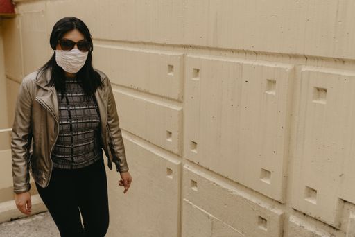 A young Hispanic female wearing a facemask and sunglasses and walking through a hallway - COVID-19