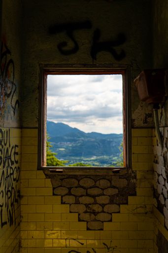 A vertical closeup of an open square shape window on an old stone building from inside