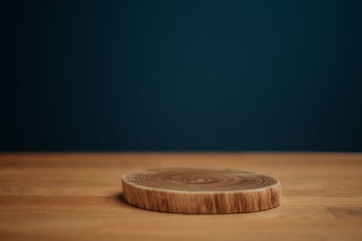 A piece of cut wood on a wooden surface in front of a dark blue background