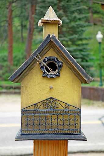 A vertical shot of a wooden birdhouse in the park