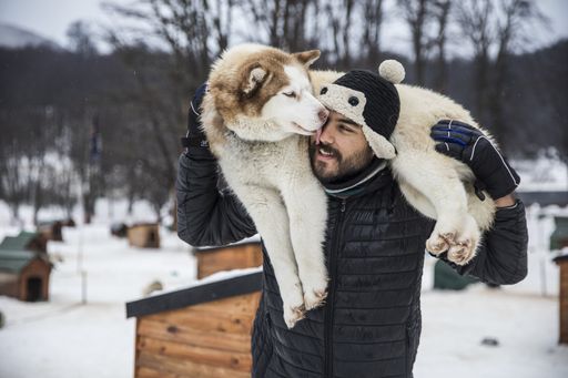 A selective focus shot of a young Hispanic male holding an adorable husky