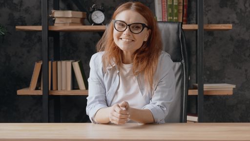 A beautiful Caucasian woman sitting on her office and wearing glasses with smile to the camera