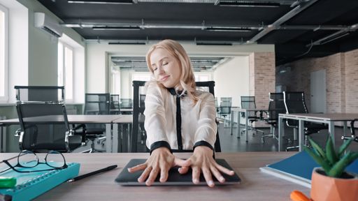 A closeup shot of Caucasian woman sitting on her office and hands on laptop while closing eyes and feeling good