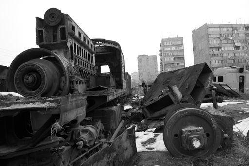A grayscale close-up of train waste with buildings on the background