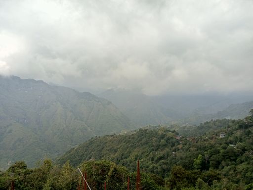 A beautiful landscape view of green Mountain with fog on the gray cloudy sky