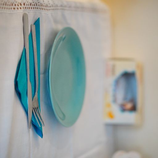 A closuep shot of a blue plate with spoon and knife on a table with white tablecloth