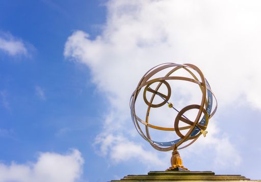 A low angle shot of a ball sundial against a blue cloudy sky
