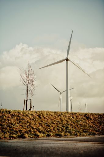 The wind turbines on a cliff in a field against a cloudy sky