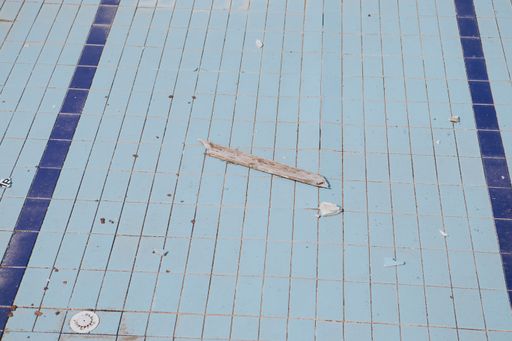 A closeup shot of a swimming pool ground without water and dirty in daylight