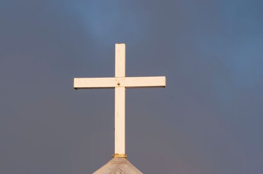 A simple white wooden cross on a church lit by Late afternoon sun, symbolising christianity, In Otaki, Kapiti, New Zealand