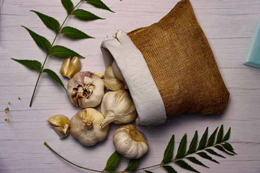 A top view of garlics with leaves on a white wooden table