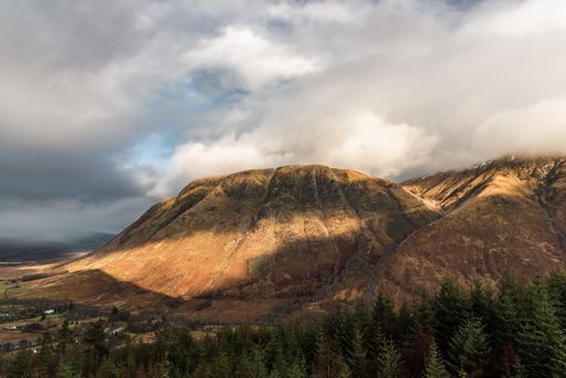 A beautiful scenery of a mountainous landscape with rocky hills under dark storm clouds