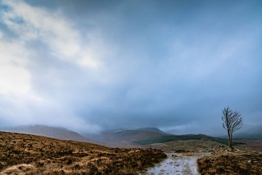 A beautiful scenery of a mountainous landscape with rocky hills under dark storm clouds