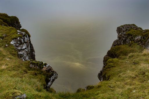 A beautiful scenery of rocky cliffs with greenery by the sea under a cloudy sky