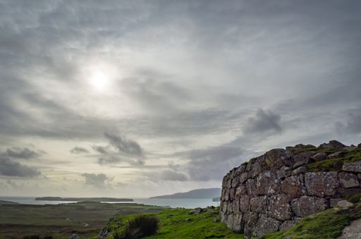 A beautiful scenery of rocky cliffs with greenery by the sea under a cloudy sky