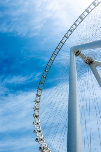 A vertical low angle shot of the Ain Dubai Ferris wheel against a blue sky in Bluewaters Island, Dubai, United Arab Emirates